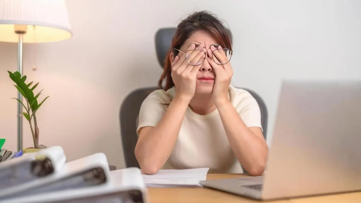Woman rubbing tired dry eyes at desk