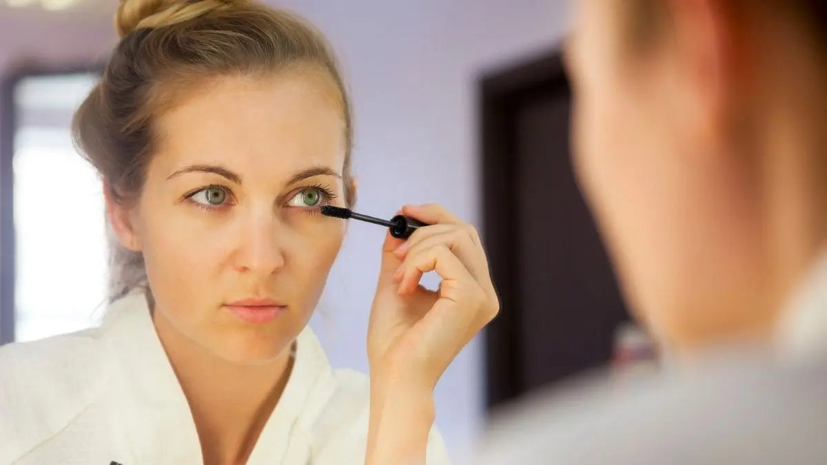 Woman applying eye makeup in mirror