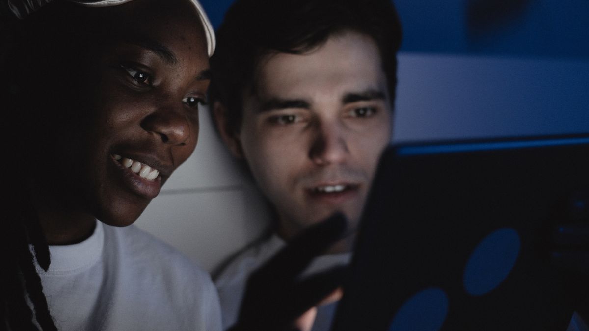 Person using an iPad in a dark bedroom at night with screen light on their face