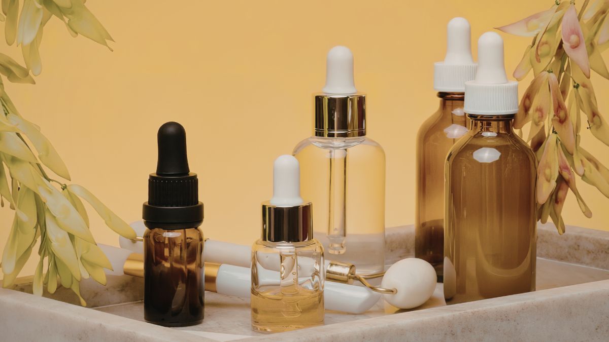 Cosmetic_ingredients._bown_tansparent_and_translucent_pippette_bottles_on_a_marble_tray_with_a_yellow_background.